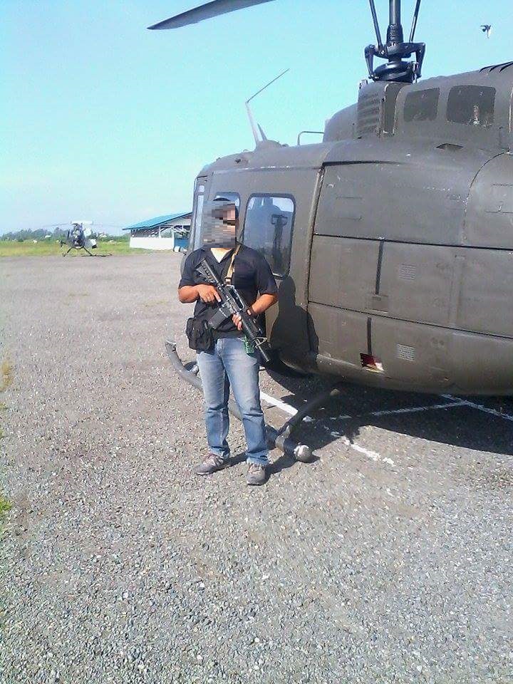 a man holding an assault rifle near helicopter.jpeg