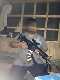a man holding an m16 rifle sitting.jpeg